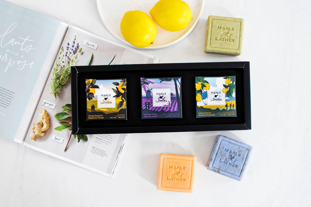 Triple-milled soap, soy candles, and luxury turkish bath rote next to beaded bracelets on white countertop.